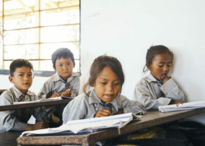 Schulkinder sitzen an Schulbank und lernen