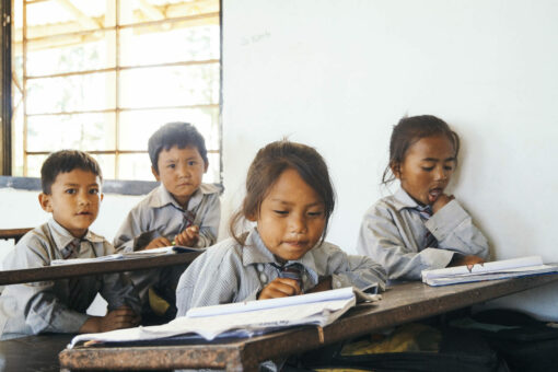 Schulkinder sitzen an Schulbank und lernen