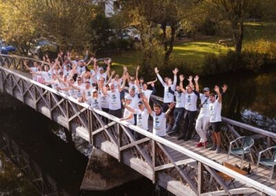 group picture of many people standing on a bridge and putting their hands up happy