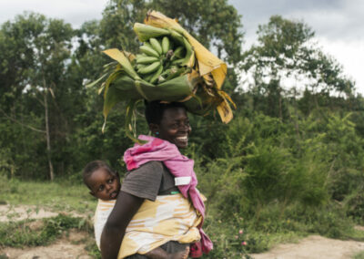 Frau mit Kind auf Rücken und Bananen auf Kopf