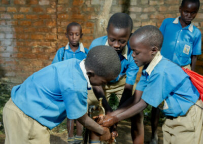 Kindern in Uganda waschen sich an einem Brunnen die Hände mit Wasser