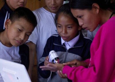 Fünf Kinder untersuchen gemeinsam ein technisches Gerät im Unterricht in Peru